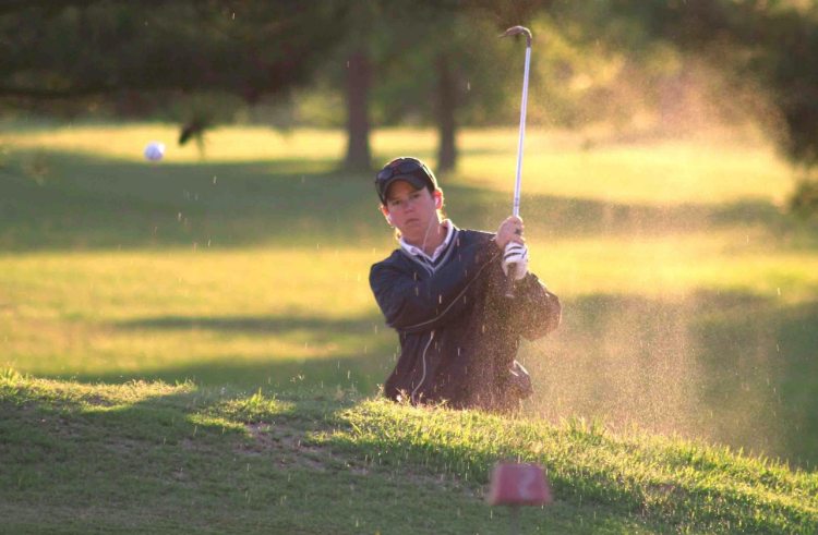 Person hitting golf ball out of sand
