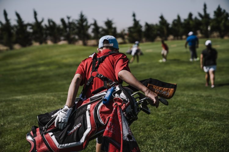 Man walking with black and red golf bag on golf course
